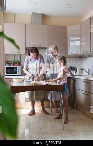 Drei Generationen von Frauen kochen gemeinsam in der Küche. Stockfoto