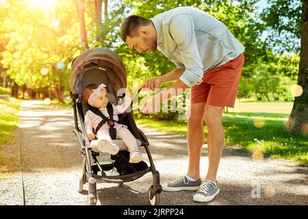 Vater mit Kind sitzt im Kinderwagen im Park Stockfoto