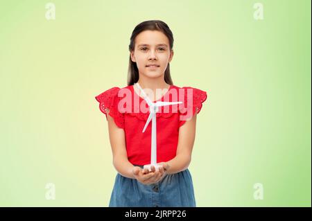 Lächelndes Mädchen mit Spielzeug Windturbine über grün Stockfoto