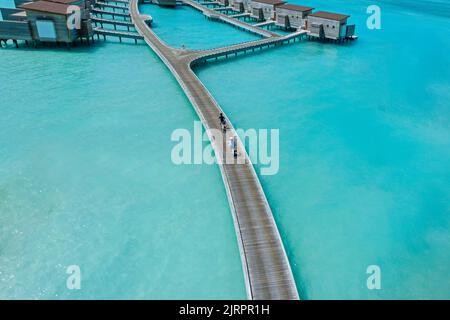 Luftaufnahme eines Paares, das mit dem Fahrrad auf dem Steg im Meer fährt Stockfoto