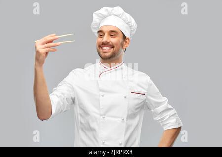 Fröhlich lächelnder männlicher Koch mit Essstäbchen Stockfoto