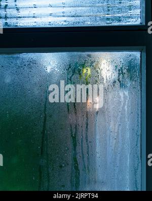 Kondensation auf der Innenseite eines einzelnen verglasten Fensters in einem kalten, feuchten Haus. Stockfoto