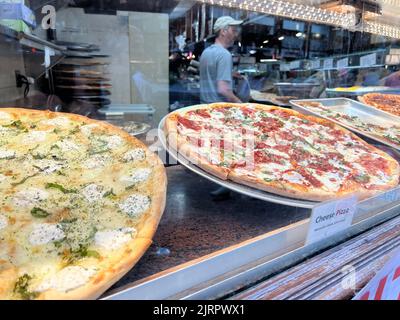 Frisch zubereitete Pizza, die in einer Pizzeria in Manhattan, New York City, am Fenster ausgestellt wird. Stockfoto