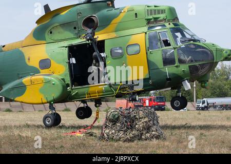 Ein rumänischer Hubschrauber der Luftwaffe IAR 330 Puma bereitet sich auf den Transport von Fracht der US-Armee vor, die von Soldaten der Bravo Company, 39. Brigade Engineer Bataillon, 101. Airborne Division (Air Assault) während der Übungsschlingentraglasoperationen mit 572. Helicopter Squadron auf der Mihail Kogălniceanu Air Base, Rumänien, am 24. August 2022, gesichert wurde. Das Hubschraubertraining bot US-Soldaten die Möglichkeit, die richtigen Methoden und Praktiken für die Vorbereitung und Ausführung von Schlingelasten und medizinischen Evakuierungszügen mit einem NATO-Verbündeten-Flugzeug zu erlernen. (USA Armeefoto von PFC. Destinee Rodriguez) Stockfoto