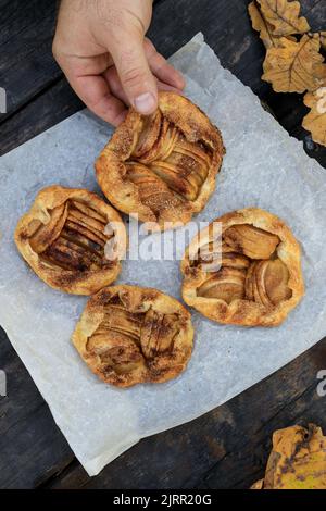 Hält in der Hand einen rustikalen traditionellen französischen Kekskuchen mit Äpfeln im herbstlichen Stil, Draufsicht. Stockfoto