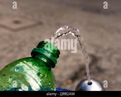 Trinkwasser in eine leere Plastikflasche füllen. Frisches Wasser aus einem öffentlichen Wasserspender in einem städtischen Gebiet. Ein kostenloser Service der Regierung. Stockfoto