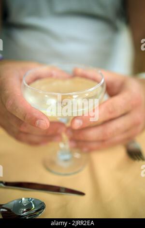 Glas mit Champagner-Cocktail in männlichen Händen, Nahaufnahme in Unschärfe. Stockfoto