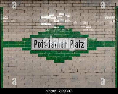 U-Bahn-Station Potsdamer Platz in Berlin. Altes Design mit gefliester Wand außen. Schwarze Buchstaben auf einem weißen Brett. Namensschild der U-Bahn-Station. Stockfoto