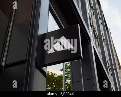 Adidas-Logo auf dem Äußeren eines Gebäudes. Eine große deutsche Modemarke für Schuhe und Sportbekleidung. Zeichen der bayerischen Firma auf einer Gebäudefassade. Stockfoto