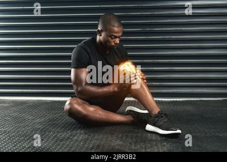 Er fühlte Schmerzen in seinem Knie. Studio-Aufnahme eines sportlichen jungen Mannes, der während seines Trainings eine Knieverletzung untersucht. Stockfoto