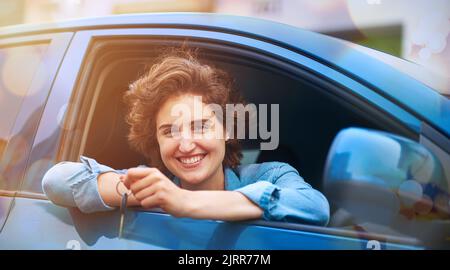 Glück ist, immer Ihr erstes Auto. Eine glückliche junge Frau hält die Schlüssel zu einem neuen Auto. Stockfoto