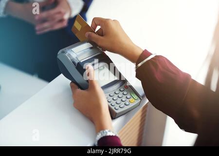 Zahlung per Karte. Eine unkenntliche Person zieht eine Kreditkarte zur Zahlung. Stockfoto