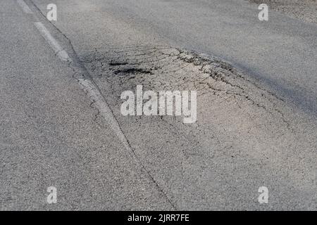 Deformierte Asphaltoberfläche mit Schlaglöchern, die durch schwere überlastete Lkw auf der Autobahn verursacht werden Stockfoto