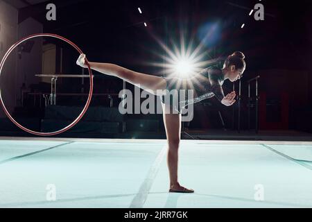 Gymnastik, Tanz und Sport mit einer Frau Turnerin Leistung auf einem Boden mit einem Reifen oder Ring. Olympische Spiele, Rhythmus und agile Tänzerin, die eine Routine spielt Stockfoto