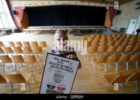 Hamburg, Deutschland. 07.. Juli 2022. Der Hausmeister André Schulz steht im Auditorium der Albert Schweitzer High School und hält den Platin-Preis für die MTV-Unplugged-CD der Band die Ärzte entgegen. Die Schule wurde vor 20 Jahren zur Rock'n'Roll-Schule, als die Band die Ärzte am 31. August 2002 ihr MTV-Unplugged-Konzert zusammen mit dem Schulorchester im Auditorium aufnahm. Die Schule profitiert noch heute von diesem musikalischen Ereignis. Seitdem finden zum Beispiel regelmäßig Dreharbeiten an der High School statt. Kredit: Marcus Brandt/dpa/Alamy Live Nachrichten Stockfoto