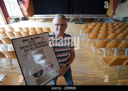 Hamburg, Deutschland. 07.. Juli 2022. Der Hausmeister André Schulz steht im Auditorium der Albert Schweitzer High School und hält den Platin-Preis für die MTV-Unplugged-CD der Band die Ärzte entgegen. Die Schule wurde vor 20 Jahren zur Rock'n'Roll-Schule, als die Band die Ärzte am 31. August 2002 ihr MTV-Unplugged-Konzert zusammen mit dem Schulorchester im Auditorium aufnahm. Die Schule profitiert noch heute von diesem musikalischen Ereignis. Seitdem finden zum Beispiel regelmäßig Dreharbeiten an der High School statt. Kredit: Marcus Brandt/dpa/Alamy Live Nachrichten Stockfoto