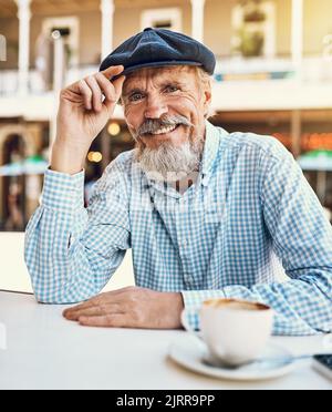 Wie du es thast. Porträt eines glücklichen älteren Mannes, der eine Tasse Kaffee in einem Straßencafé genießt. Stockfoto