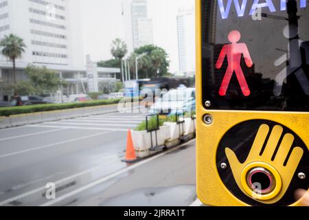 Warten Sie auf das Schild, das sich an der Fußgängerzone an einer belebten Straße befindet Stockfoto