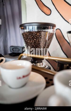 Frische dunkelbraune Kaffeebohnen in einer Kaffeemühle in einer Ecke eines Coffee Shops Stockfoto