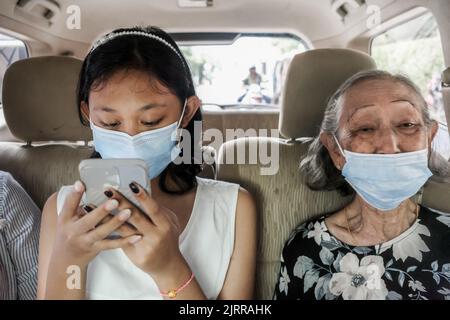 Asiatisches Teenager Mädchen und Oma tragen Gesichtsmasken im Auto Stockfoto