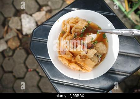 Leckeres indonesisches Streetfood Bakwan malang serviert in einer Schüssel auf einem Hocker Stockfoto