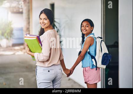 Sie nimmt ihre Schüler unter ihre Fittiche. Porträt einer attraktiven jungen Lehrerin, die eine ihrer Schüler zur Klasse führt. Stockfoto