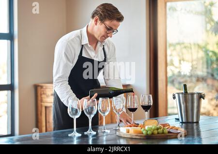 Kellner, Weinverkostung und Barkeeper mit Glas im feinen Weinbergrestaurant auf dem Land. Professioneller Sommelier, der Qualität und Luxus ausgießt Stockfoto