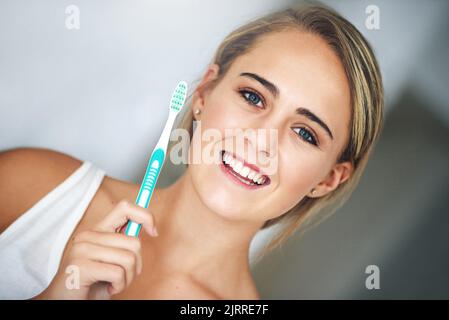 Das erste, was Sie im Kopf haben sollten, ist Ihre Zahnbürste. Porträt einer attraktiven jungen Frau, die sich im Badezimmer die Zähne putzt. Stockfoto
