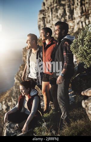 Die Aussicht von oben ist immer die beste. Eine Gruppe von Freunden bewundern die Aussicht beim Wandern in den Bergen. Stockfoto