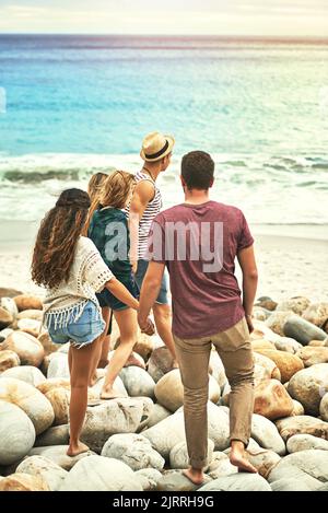 Auf dem Weg zum Wasser. Rückansicht von zwei Pärchen, die am Strand zum Wasser gingen. Stockfoto