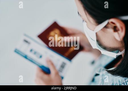 Eine Frau, die während der covid Pandemie mit ihrem Pass und ihrem Flugticket am Flughafen reist. Ein Tourist, der das Land aufgrund der Leichtigkeit verlassen Stockfoto