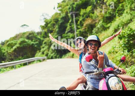 Die Liebe zum Wind in den Haaren. Ein glückliches junges Paar, das mit dem Roller ein exotisches Ziel erkundet. Stockfoto