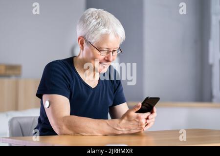 Frau Testend Glukosespiegel Mit Kontinuierlichem Glukosemonitor Auf Mobile Telefon Stockfoto