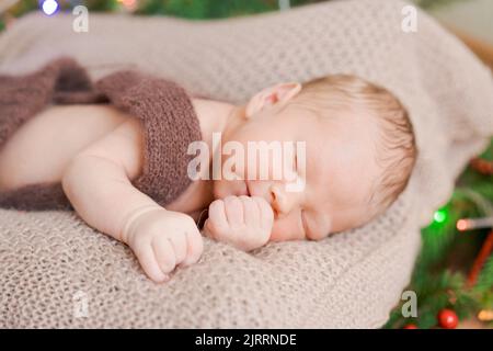 Ein süßes Neugeborenes schläft auf einer gestrickten Bettdecke, ein gesundes und niedliches Baby in den ersten Tagen des Lebens Stockfoto