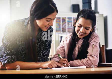 Sie schenkt ihren Schülern eine Einzelaufmerksamkeit. Eine junge Lehrerin hilft einer Schülerin in ihrem Klassenzimmer. Stockfoto