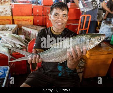 Indonesien, Juni 13 2022 - der Mann hält stolz große Fische, die er auf dem Markt verkauft. Stockfoto