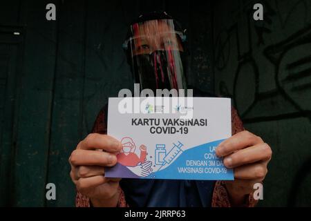 Temanggung, Central Java, Indonesien, 23. September 2021: Bürger zeigt Impfkarte. Durch diese Methode wird erwartet, dass die Teilnahme an Impfungen zunehmen wird, da sie Familien erreichen kann, die keinen Zugang haben und Angst haben, das Haus zu verlassen, um die Übertragung des Virus zu vermeiden. Stockfoto