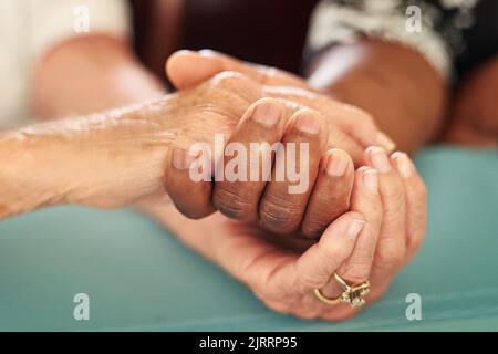 Mit Mitgefühl ist alles möglich. Eine ältere Frau, die ihre Freunde mit Trost in die Hände hält. Stockfoto