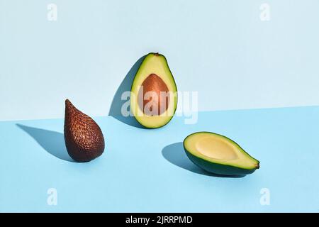 Zusammensetzung aus frischen Früchten, Salakka und zwei Hälften ausgeschnittenem Avocado auf zweifarbigem Hintergrund Stockfoto