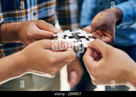 Praktische Übungen im Problemlösungsprozess. Eine Arbeitsgruppe, die Teile eines Puzzles verbindet. Stockfoto