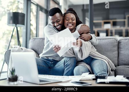 Lächelndes, glückliches und umarmendes Paar, das zu Hause die gemeinsame Arbeit genießt, umarmt und liebt. Junge romantische Partner arbeiten online und feiern Stockfoto