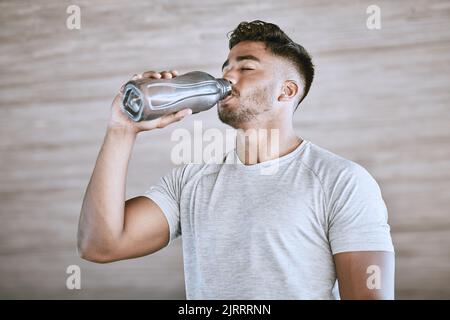 Fitnessläufer nach dem Training, gesundes Trinkwasser aus der Flasche und ein starker, sportlicher junger Mann macht eine Pause vom Laufen. Trainingsmotivation Stockfoto