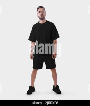 Übergroße schwarze T-Shirt-Vorlage mit Falten, Shorts mit lockerer Passform auf einem stehenden Kerl in Sneakers, isoliert auf dem Hintergrund. Anzuganzug, Kleidung Stockfoto