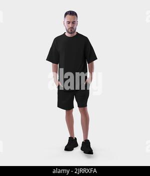 Übergroße schwarze Suit-Vorlage auf einem wandelenden Kerl mit Händen in der Tasche, isoliert auf dem Hintergrund. T-Shirt Mockup, Shorts auf einen Mann in Turnschuhen, Kleidung mit Stockfoto