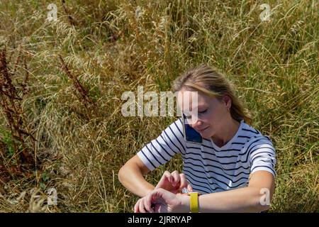 Eine Frau telefoniert und überprüft die Zeit auf ihrer Smartwatch. Stockfoto