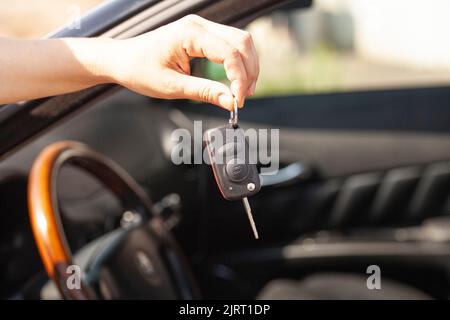 Schlüssel in der Hand einer Frau mit dem Auto Stockfoto