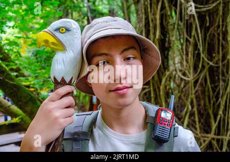 Porträt eines Jungen im Teenageralter, der einen Sonnenhut und einen Rucksack trägt und einen Spazierstock mit Adlerkopf hält, während er Muir Woods in Kalifornien, USA, besucht Stockfoto