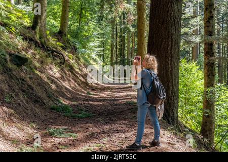 Eine blonde Frau fotografiert die Schönheiten des Naturparks Acquerino Cantagallo in Italien Stockfoto