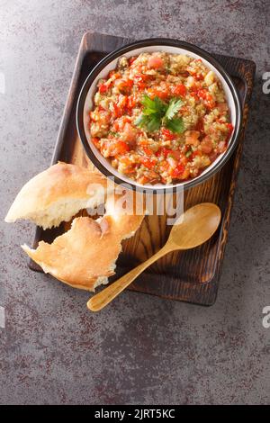 Auberginen-Kaviar mit Tomaten, Knoblauch und gerösteter Paprika-Closeup in der Schüssel auf dem Tisch. Vertikale Draufsicht von oben Stockfoto