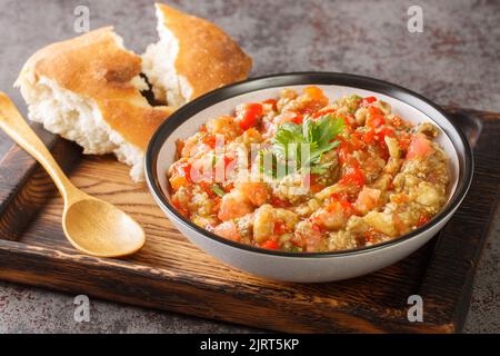 Vegetarischer Kaviarsalat mit Auberginen, Tomaten, Paprika, Knoblauch mit Olivenöl in einer Schüssel auf dem Tisch in der Nähe gewürzt. Horizontal Stockfoto